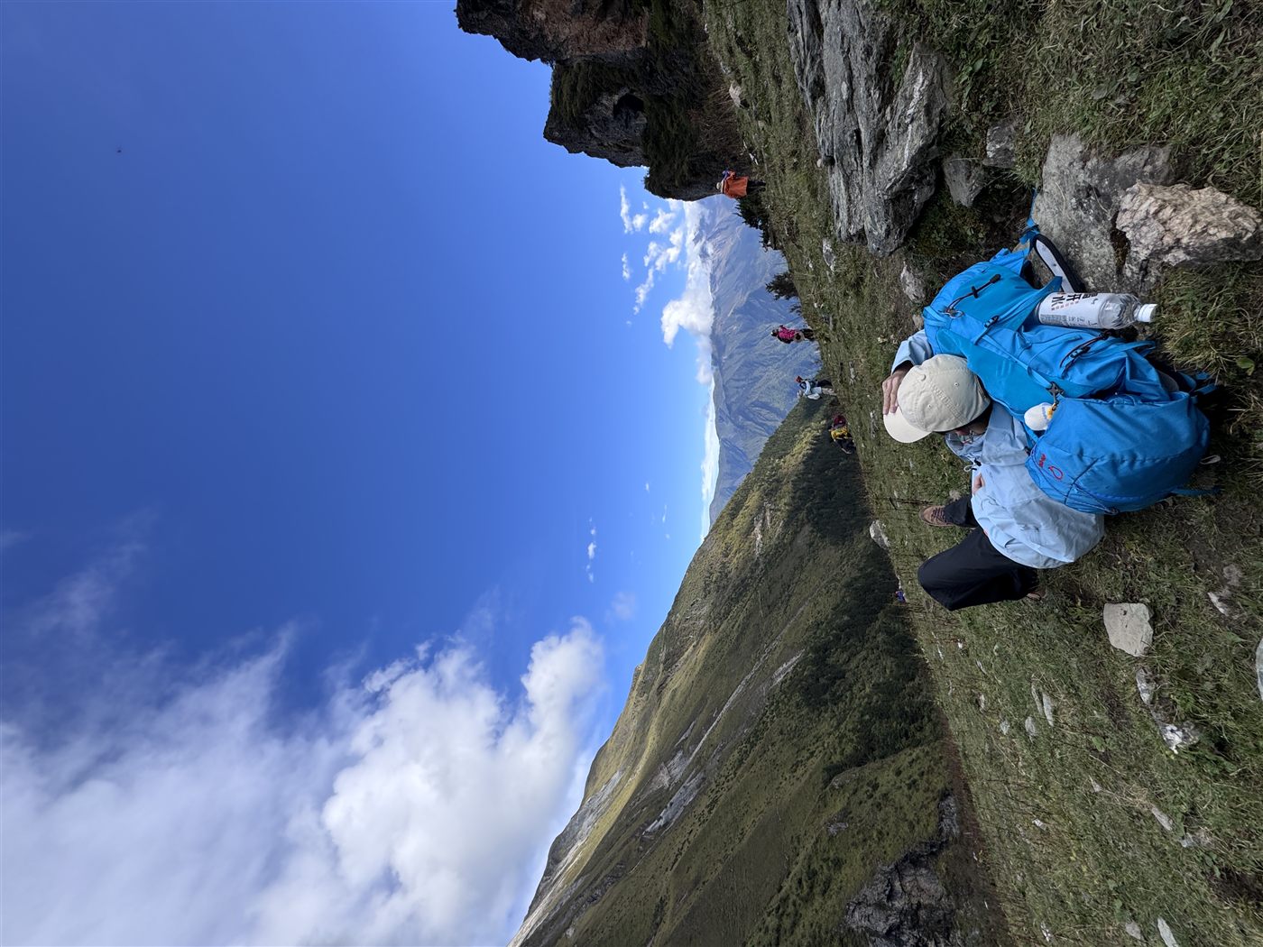山谷草坡上休息，旁边放着登山包